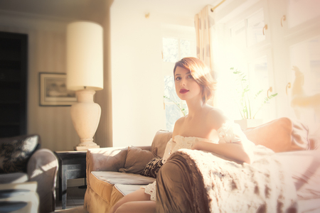 beautiful young woman sitting on the sofa in the light luxury roomの写真素材