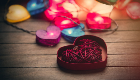 beautiful colorful heart shaped garland and toy in opened heart shaped box on the wonderful brown wooden backgroundの写真素材