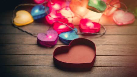 beautiful colorful heart shaped garland and opened heart shaped box on the wonderful brown wooden backgroundの写真素材