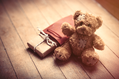 cute gift, teddy bear and cool red shopping bag on the wonderful brown wooden backgroundの写真素材