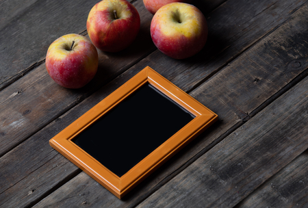 beautiful empty frame and fresh apples lying on the wonderful wooden brown backgroundの写真素材