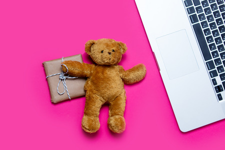 beautiful small gift, cute teddy bear and cool laptop on the wonderful pink backgroundの写真素材