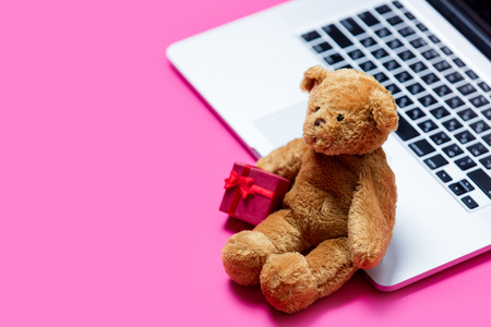 beautiful small gift, cute teddy bear and cool laptop on the wonderful pink backgroundの写真素材