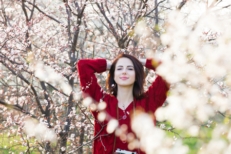 beautiful young woman standing in front of wonderful blooming treesの写真素材