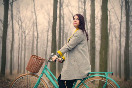 beautiful young woman sitting on the bicycle in the wonderful forestの写真素材