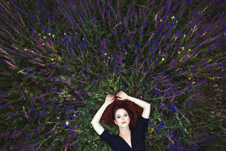 beautiful young woman lying and relaxing on the wonderful blooming lavender fieldの写真素材