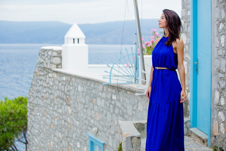photo of beautiful young woman standing on the stairs near the house in Greeceの写真素材