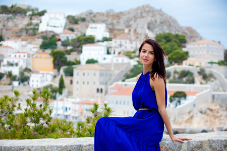 photo of beautiful young woman sitting on the stairs on the town background in Greeceの写真素材