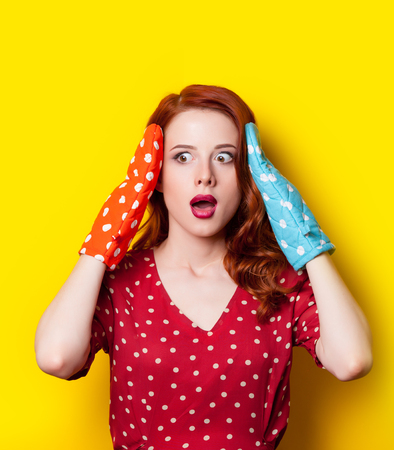 beautiful surprised young woman with colorful potholders on the wonderful yellow backgroundの写真素材