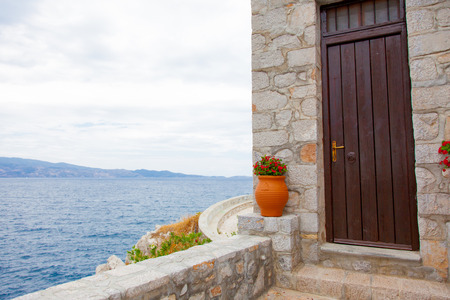 photo of cute pot with flowers near door on the wonderful sea background in Greeceの写真素材