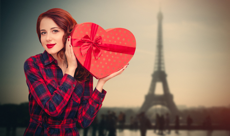 beautiful young woman holding gift on the wonderful eiffel tower backgroundの写真素材