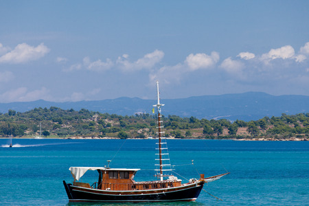 photo of cute fishing boat in front of wonderful sea and island background in Greeceの写真素材