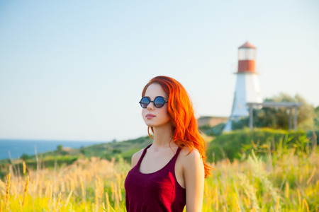 beautiful young woman standing in front of wonderful sea and lighthouse backgroundの写真素材