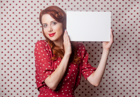 beautiful young woman holding a sheet of paper on the wonderful dotted backgroundの写真素材