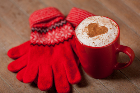 photo of cup of coffee and warm gloves on the wonderful brown wooden backgroundの写真素材