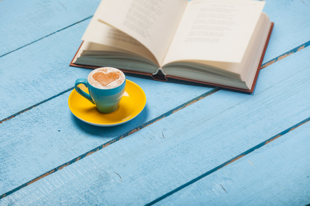 photo of cup of coffee and opened book on the wonderful blue wooden backgroundの写真素材