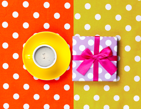 photo of cup of coffee and cute gift on the wonderful colorful dotted background in pop art styleの写真素材