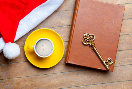 cup of coffee, golden key, book and santa claus hat on the wonderful brown wooden backgroundの写真素材