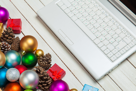 silver laptop and beautiful christmas decorations on the wonderful white wooden backgroundの写真素材