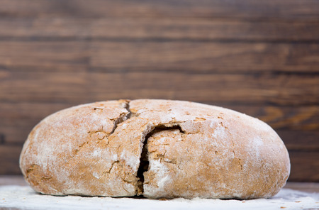 photo of tasty fresh bread loaf on the wonderful brown wooden background