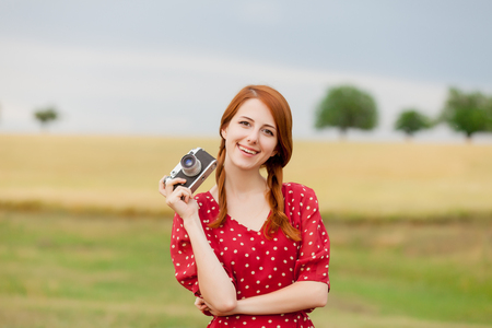 portrait of beautiful young woman holding retro camera on the wonderful wheat field backgroundの写真素材