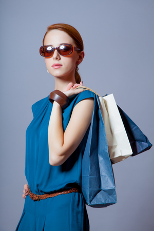 portrait of beautiful young woman with shopping bags on the wonderful grey studio backgroundの写真素材