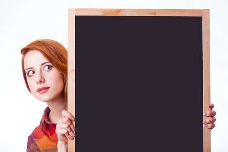 portrait of beautiful young woman with empty board on the wonderful white studio backgroundの写真素材