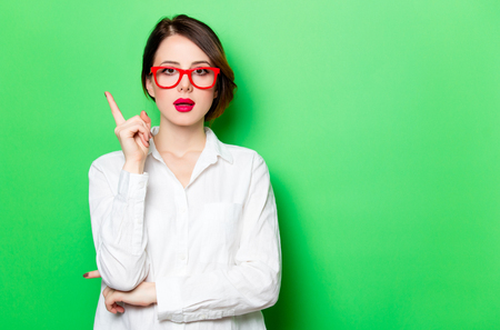 portrait of beautiful surprised young woman in glasses on the wonderful studio green backgroundの写真素材