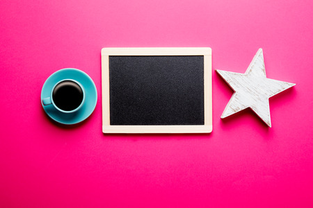 photo of cup of coffee, star shaed toy and empty blackboard on the wonderful pink studio backgroundの写真素材