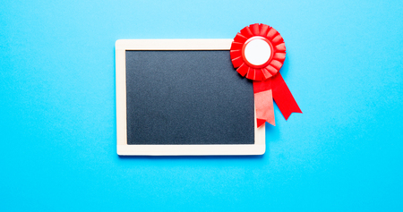 photo of cute prize ribbon and empty blackboard on the wonderful blue studio backgroundの写真素材