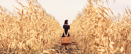 photo of beautiful young woman with suitcase on the wonderful field and sky backgroundの写真素材