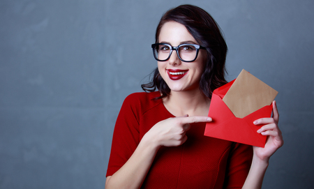 portrait of beautiful young woman holding envelope and letter in it on the wonderful grey studio...