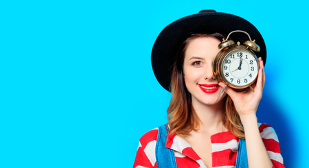 Portrait of young smiling red-haired white european woman in hat and red striped shirt with retro...