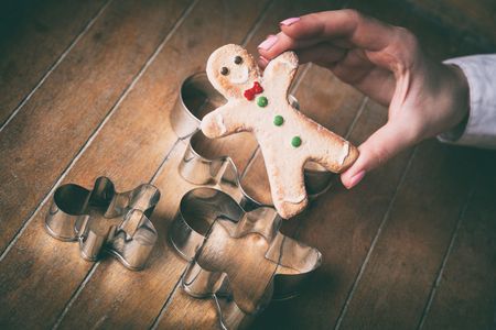 Young woman hands holding christmas gingerbread man cookie with forms on wooden background, Photo in old color image styleの写真素材