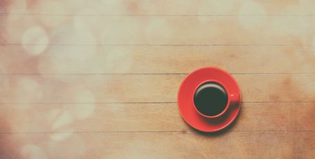 Red Cup of coffee with saucer on wooden background