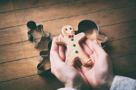 Young woman hands holding christmas gingerbread man cookie with forms on wooden background, Photo in old color image styleの写真素材
