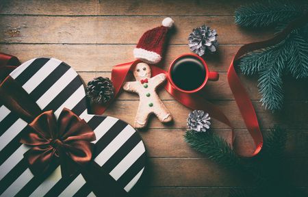 Cup of coffee and Christmas gingerbread man with pine cones and branches on wooden backgroundの写真素材