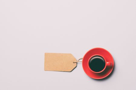 Red cup of coffee and paper tag on grey background, view aboveの写真素材