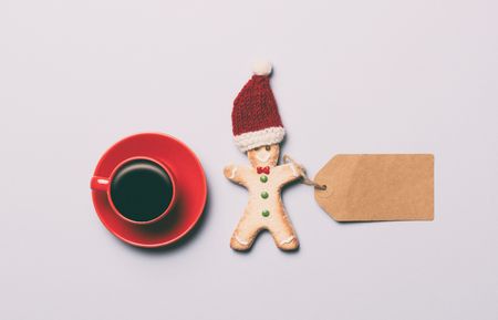 Red cup of coffee and Gingerbread man with paper tag on grey background, view aboveの写真素材