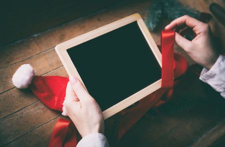 Young woman hands wrapping christmas board and gifts on wooden background, Photo in old color image styleの写真素材