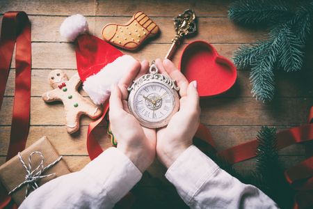 Young woman hands wrapping christmas victorian clock and gifts on wooden background, Photo in old color image styleの写真素材