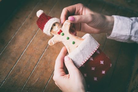 Young woman hands holding christmas gingerbread man cookie in sock on wooden background, Photo in...