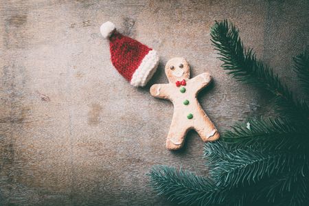 Christmas gingerbread man cookie with hat and pine branch on wooden backgroundの写真素材