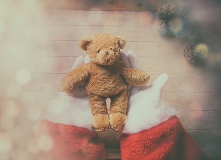 Santa Claus holding teddy bear toy on wooden background with bokehの写真素材