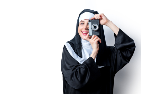 Young smiling nun with photo camera on white backgroundの写真素材