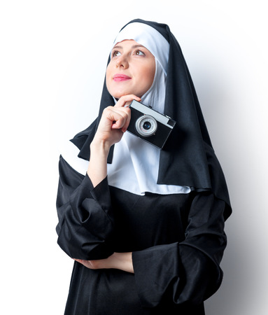 Young smiling nun with photo camera on white backgroundの写真素材
