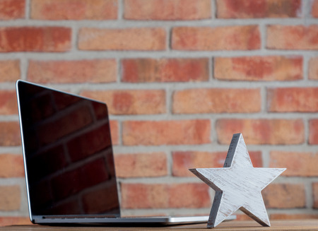 Wooden leader star and laptop on brick wall backgroundの写真素材