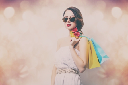 portrait of beautiful young woman with colorful shopping bags on the wonderful bokeh backgroundの写真素材