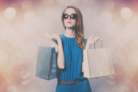 Portriat in blue costume with shopping bags and bokeh lights on backgroundの写真素材