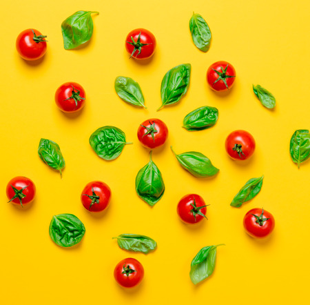 Above view at tomatoes and basil on yellow background